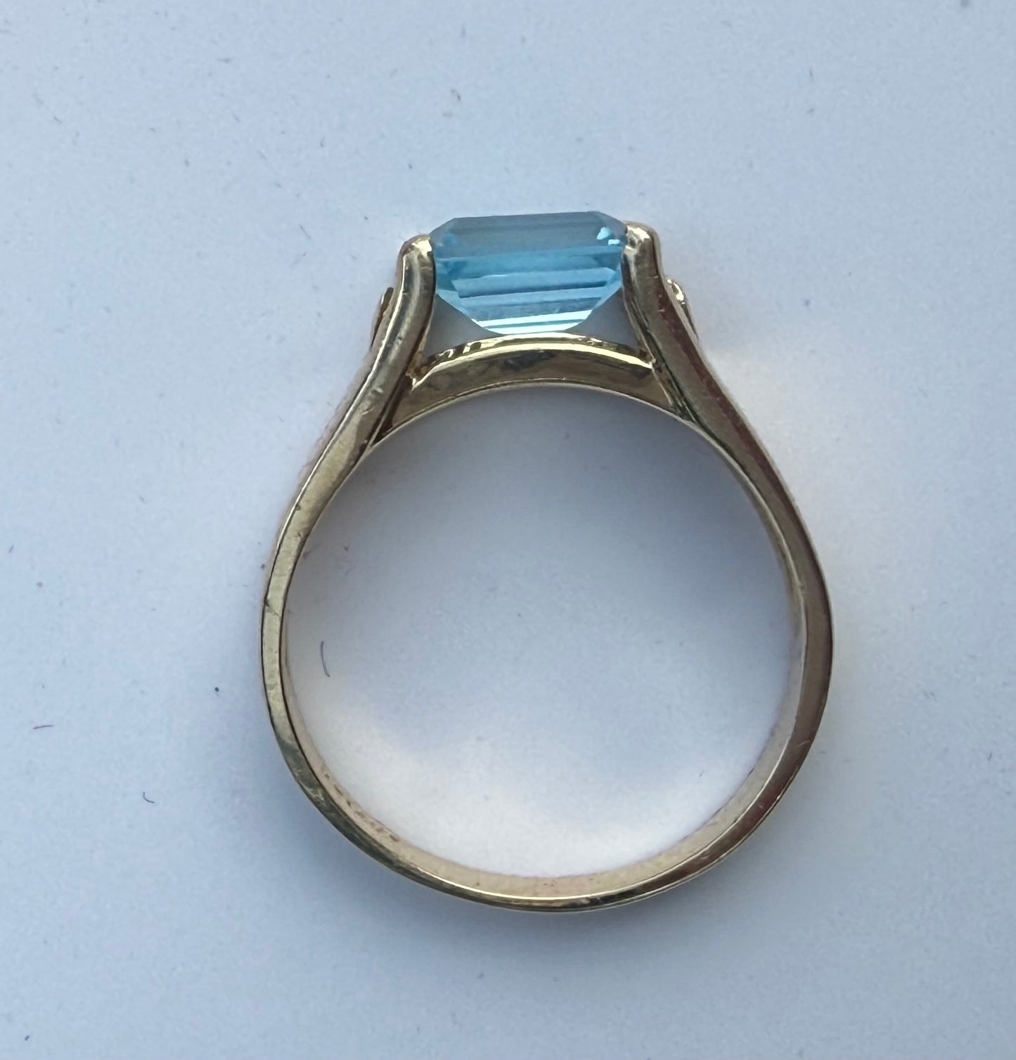 Side profile of 14K yellow gold blue topaz and diamond ring showing open under-gallery and high-set stone.