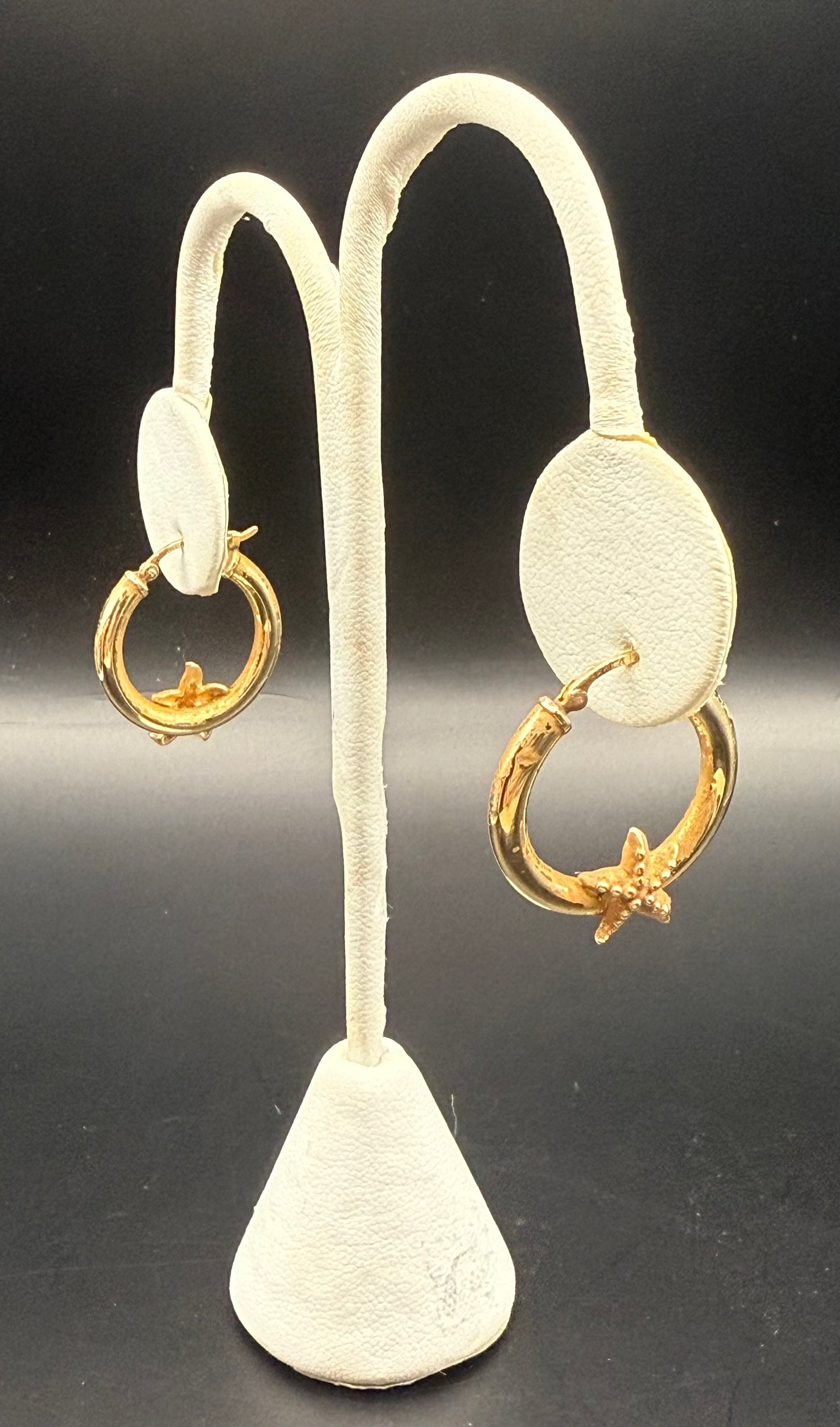 Starfish gold hoop earrings displayed on white earring stand