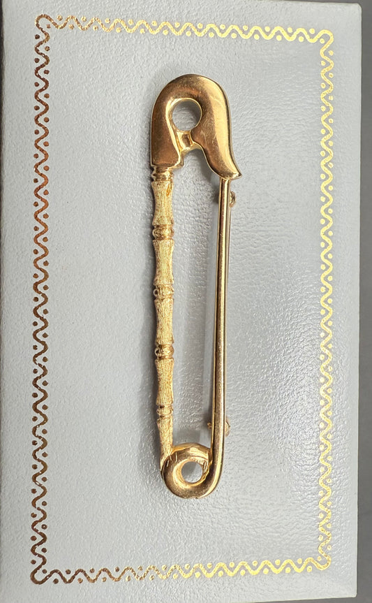 Vintage 14K yellow gold safety pin pendantbrooch with bamboo accent, displayed on decorative background