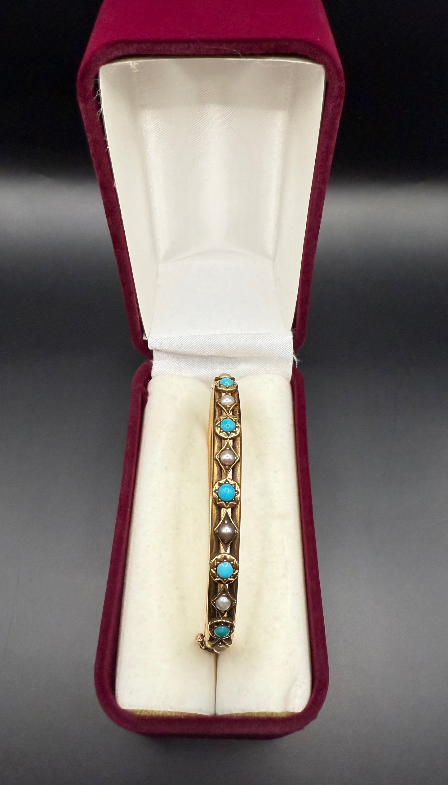 Antique Victorian turquoise and pearl bangle bracelet displayed in vintage red velvet jewelry box