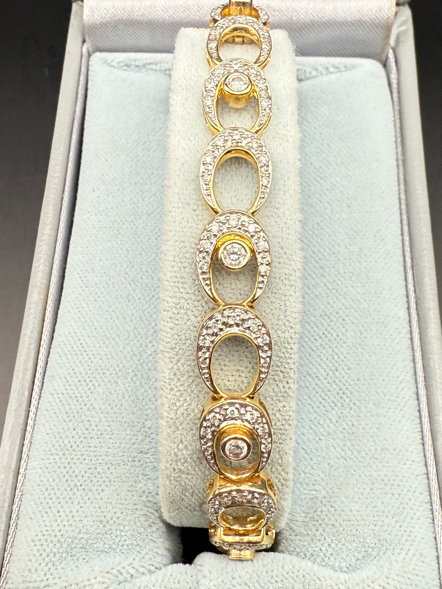 Tennis bracelet displayed in presentation box, oval diamond-set links visible