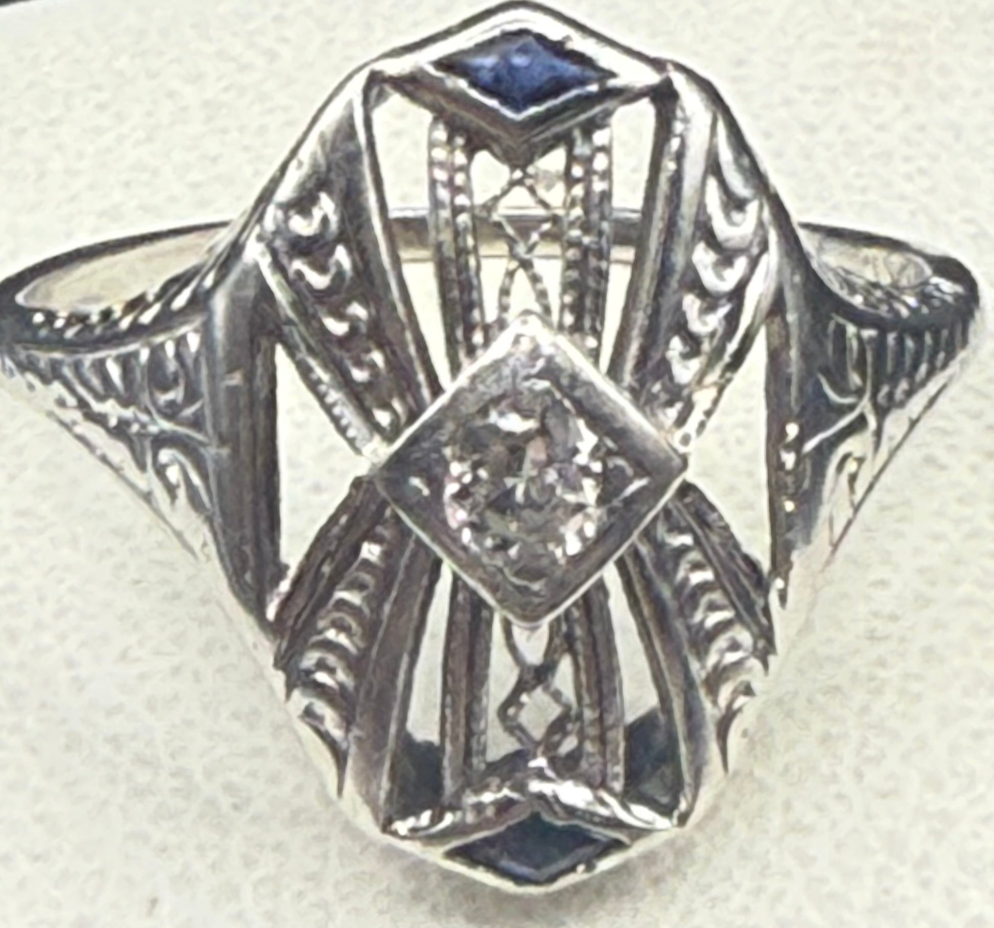 Close-up front view of Art Deco 18K white gold filigree ring with diamond and sapphire details