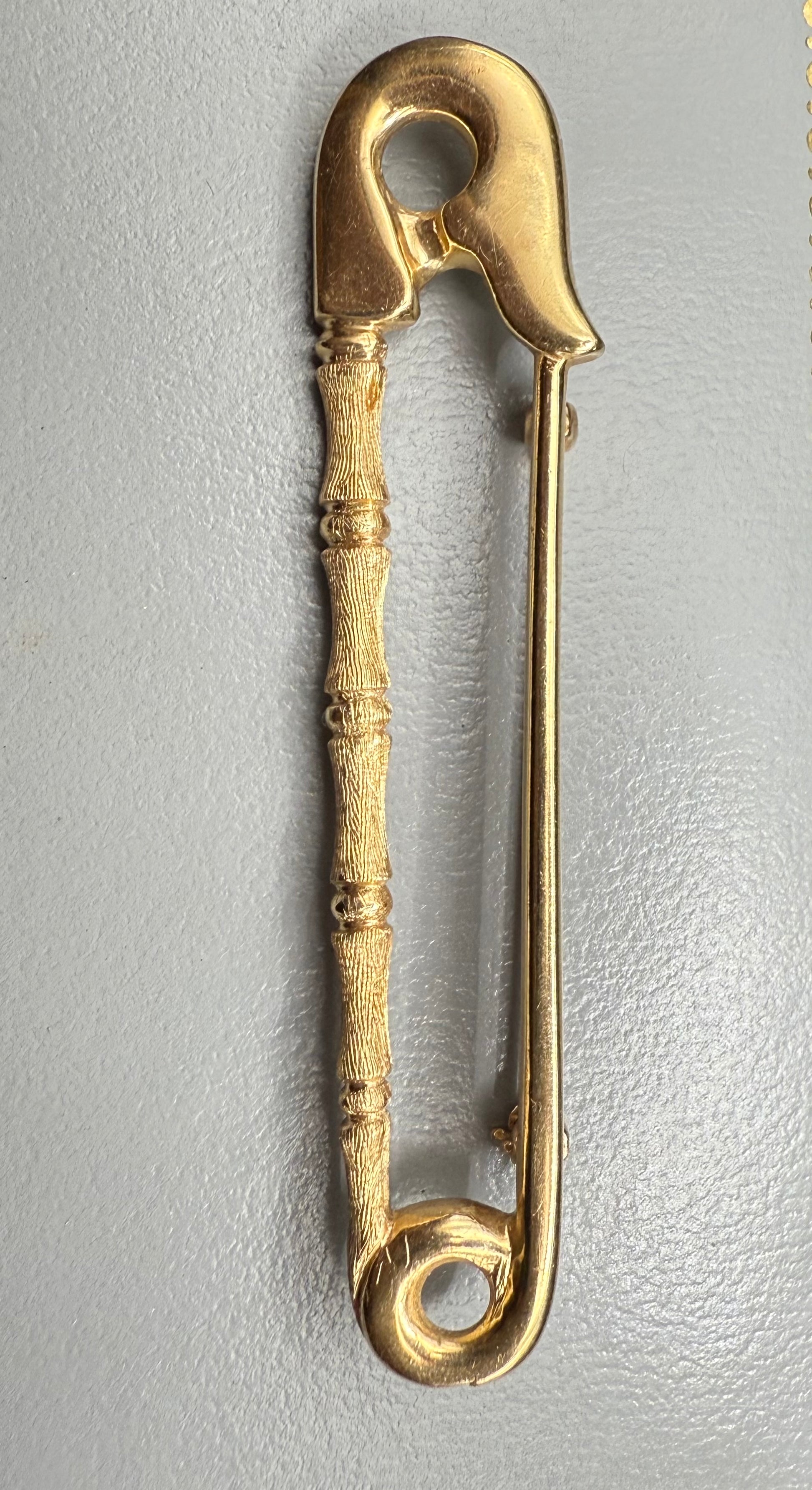 Close-up of 14K gold safety pin brooch highlighting textured bamboo detail