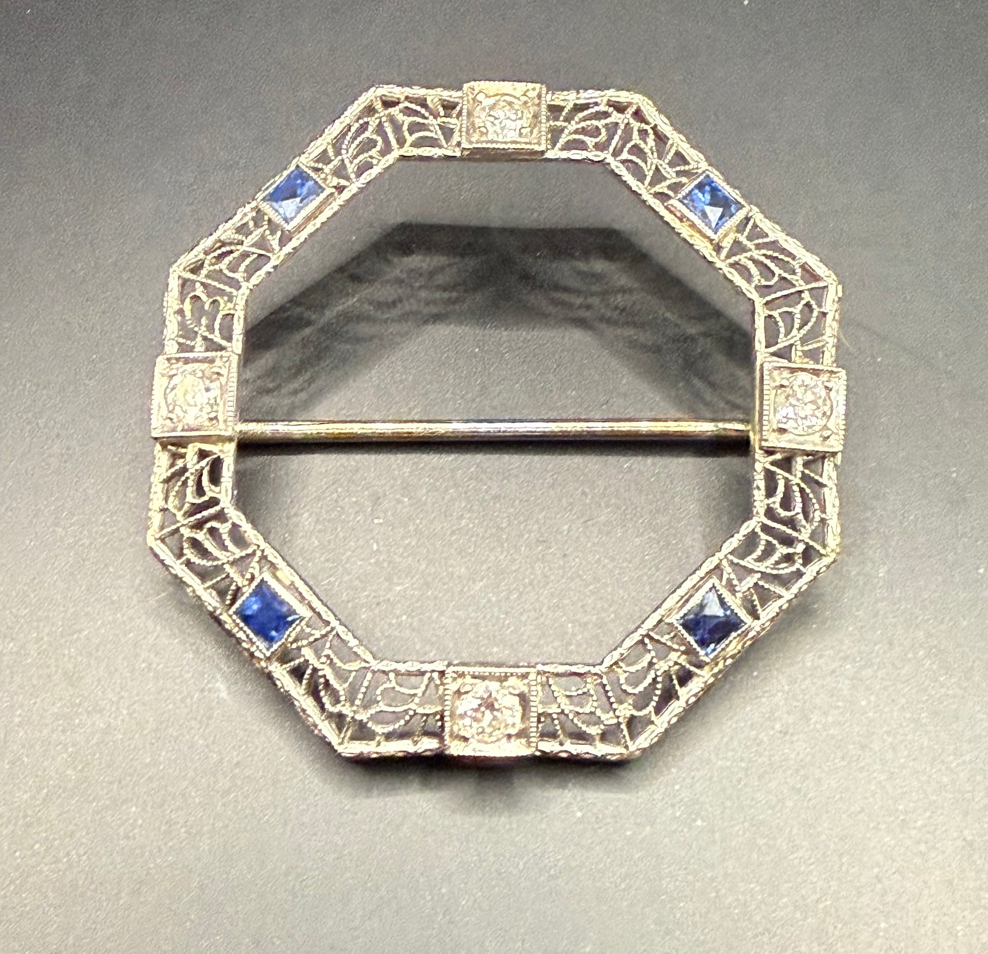 Close-up of Art Deco brooch with 4 diamonds and 4 sapphires in filigree frame