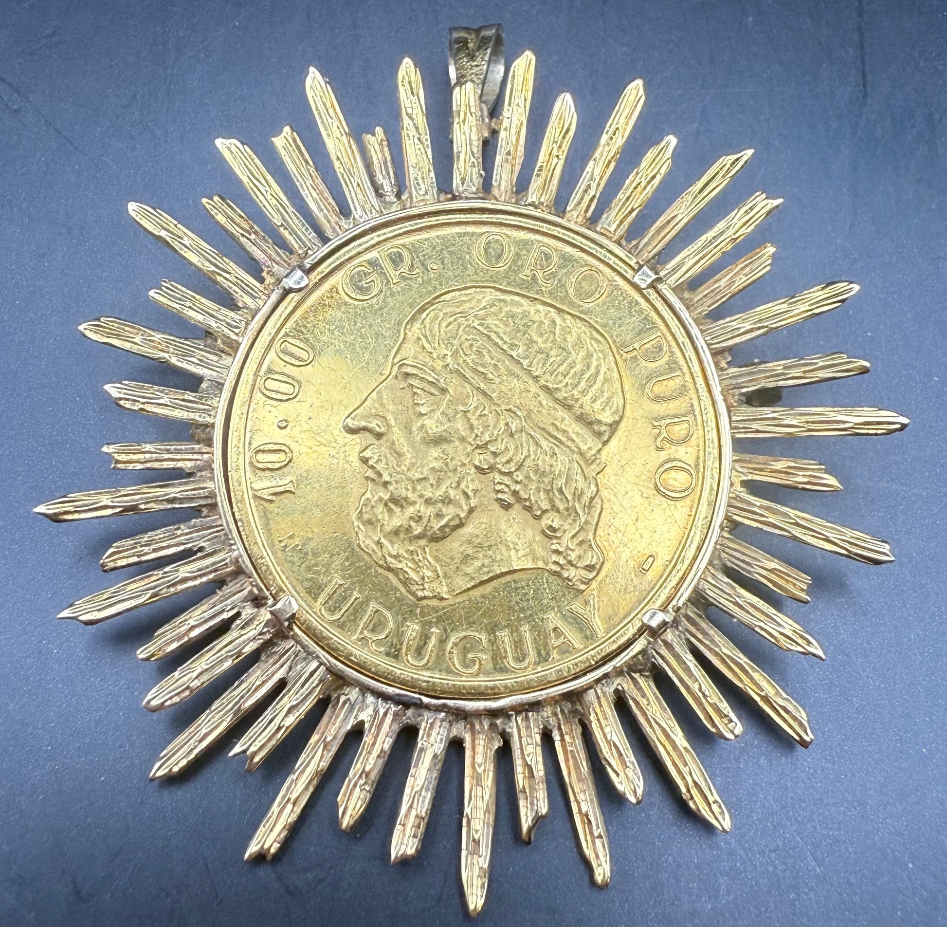 Close-up of coin face “10.00 Gr. Oro Puro Uruguay” in sunburst gold frame