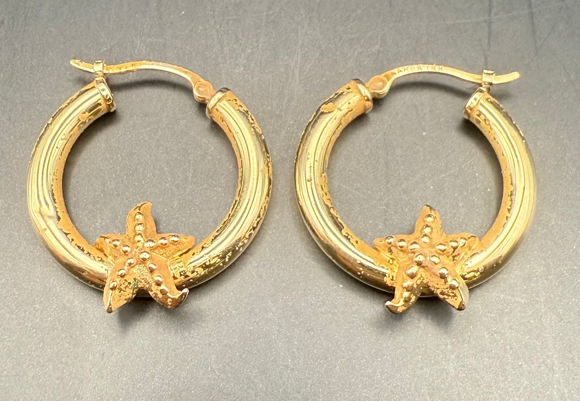 Close-up of estate gold hoops featuring starfish accents