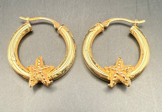 Close-up of estate gold hoops featuring starfish accents