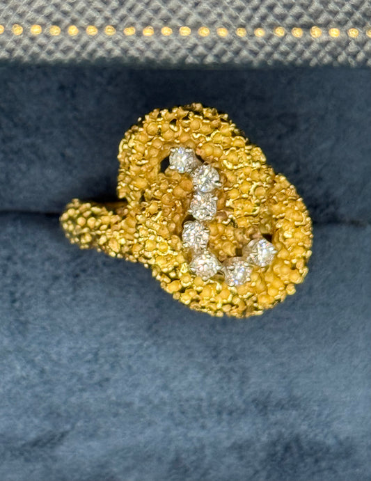 Close-up of textured coral-like gold surface with seven brilliant diamonds set in platinum.