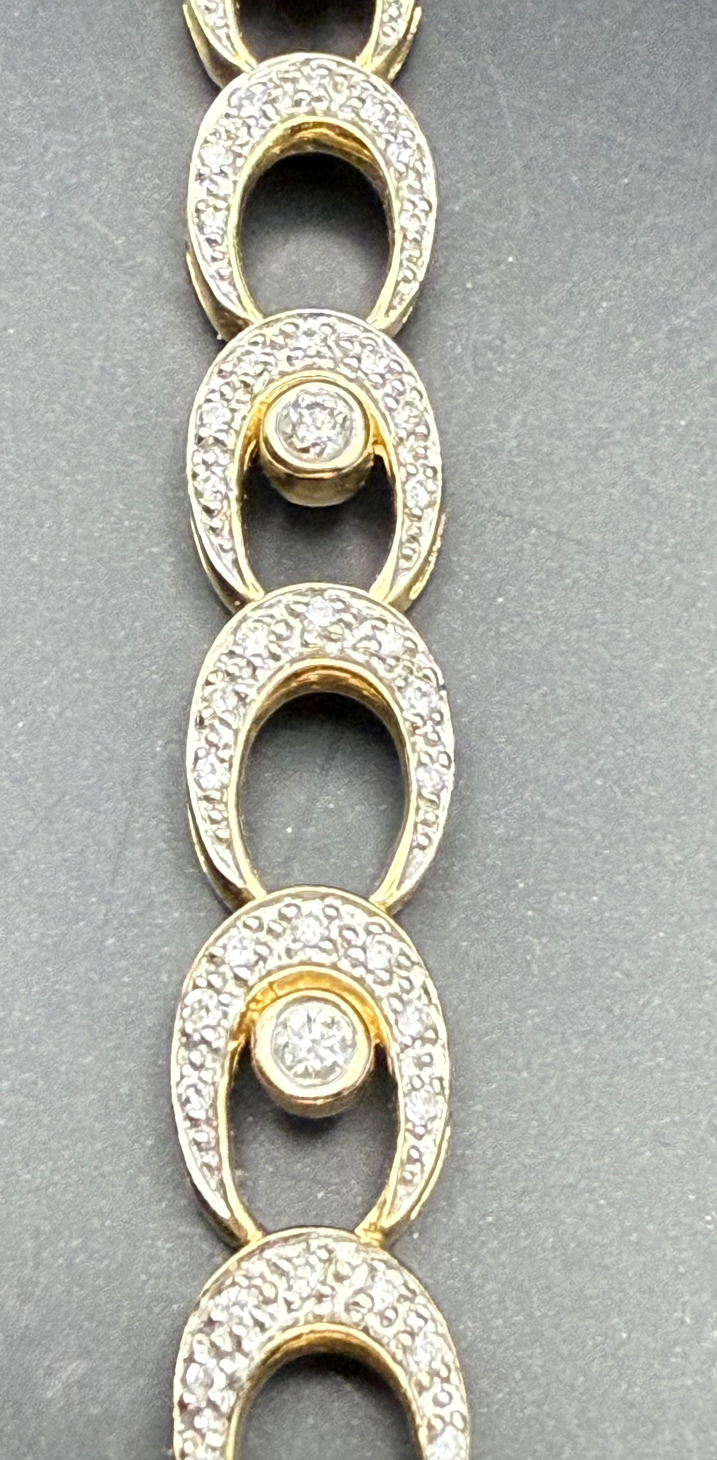 Close-up of vintage 14K yellow gold oval link bracelet with pavé-set diamonds and round center diamonds