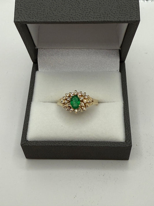 Emerald and diamond cluster ring displayed in gray presentation box