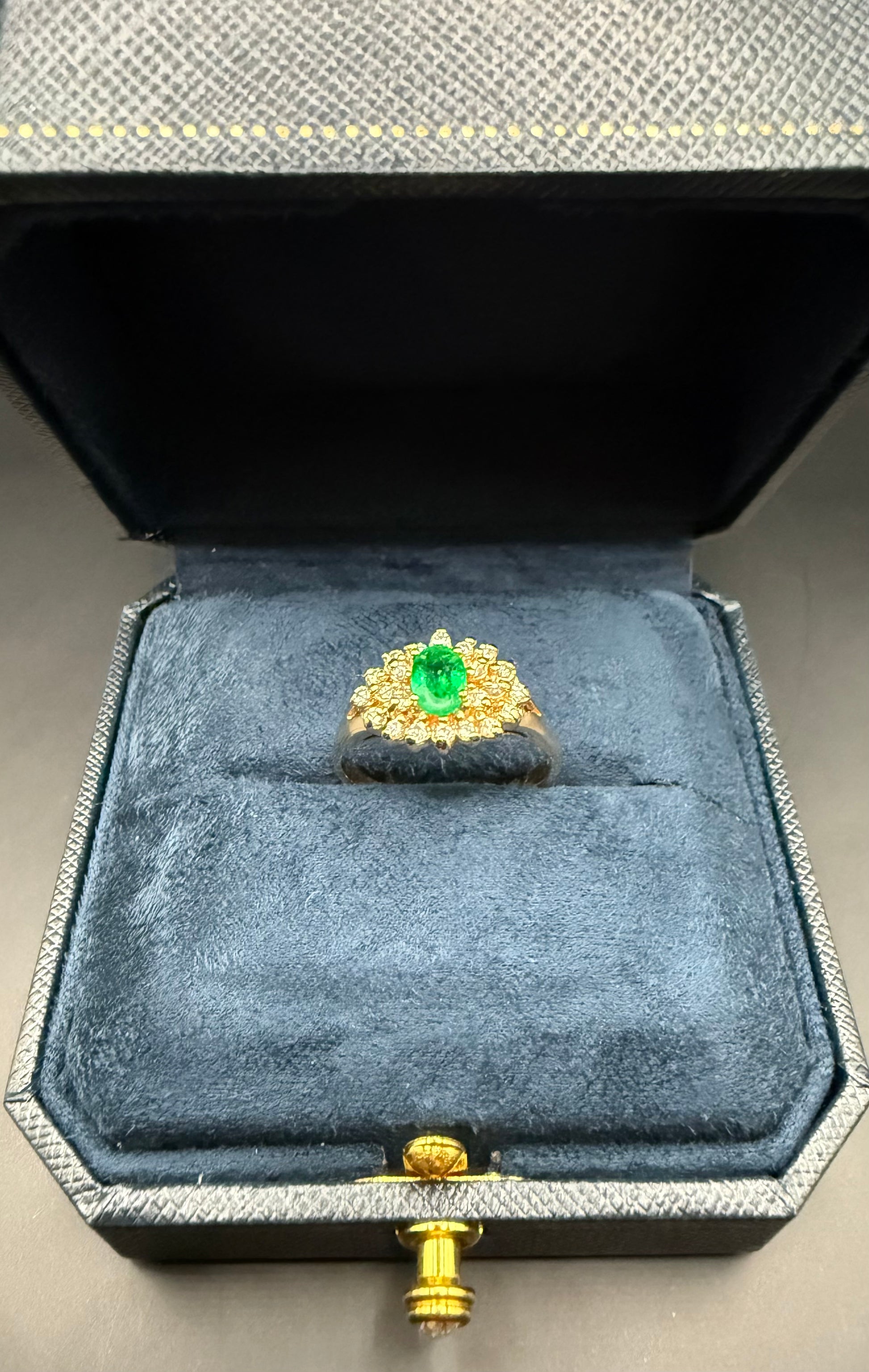 Estate 14K yellow gold emerald and diamond cluster ring displayed in navy jewelry box, front view.