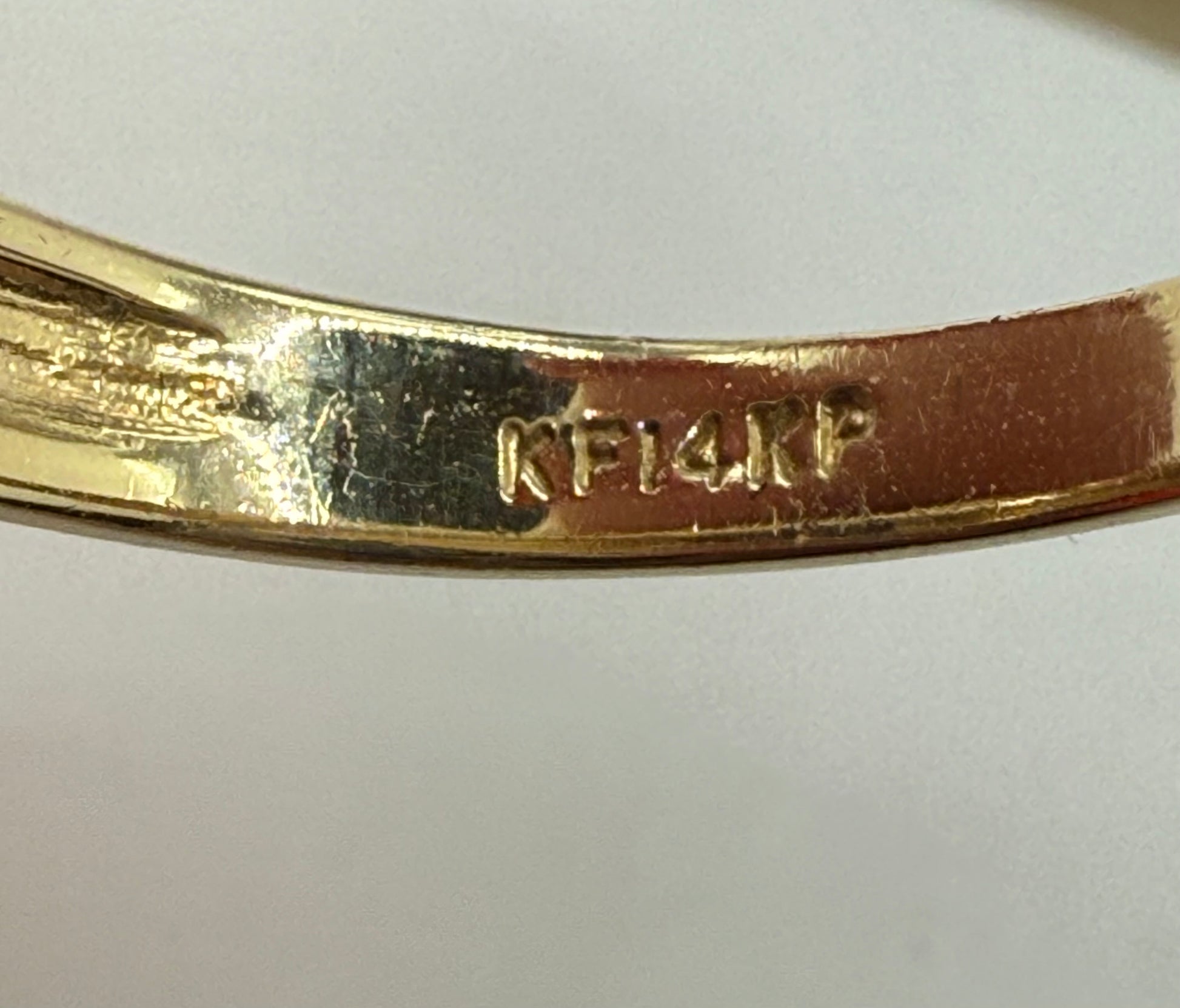 Macro view of “KF14KP” stamp inside 14K yellow gold ring band, confirming metal purity and maker’s mark.