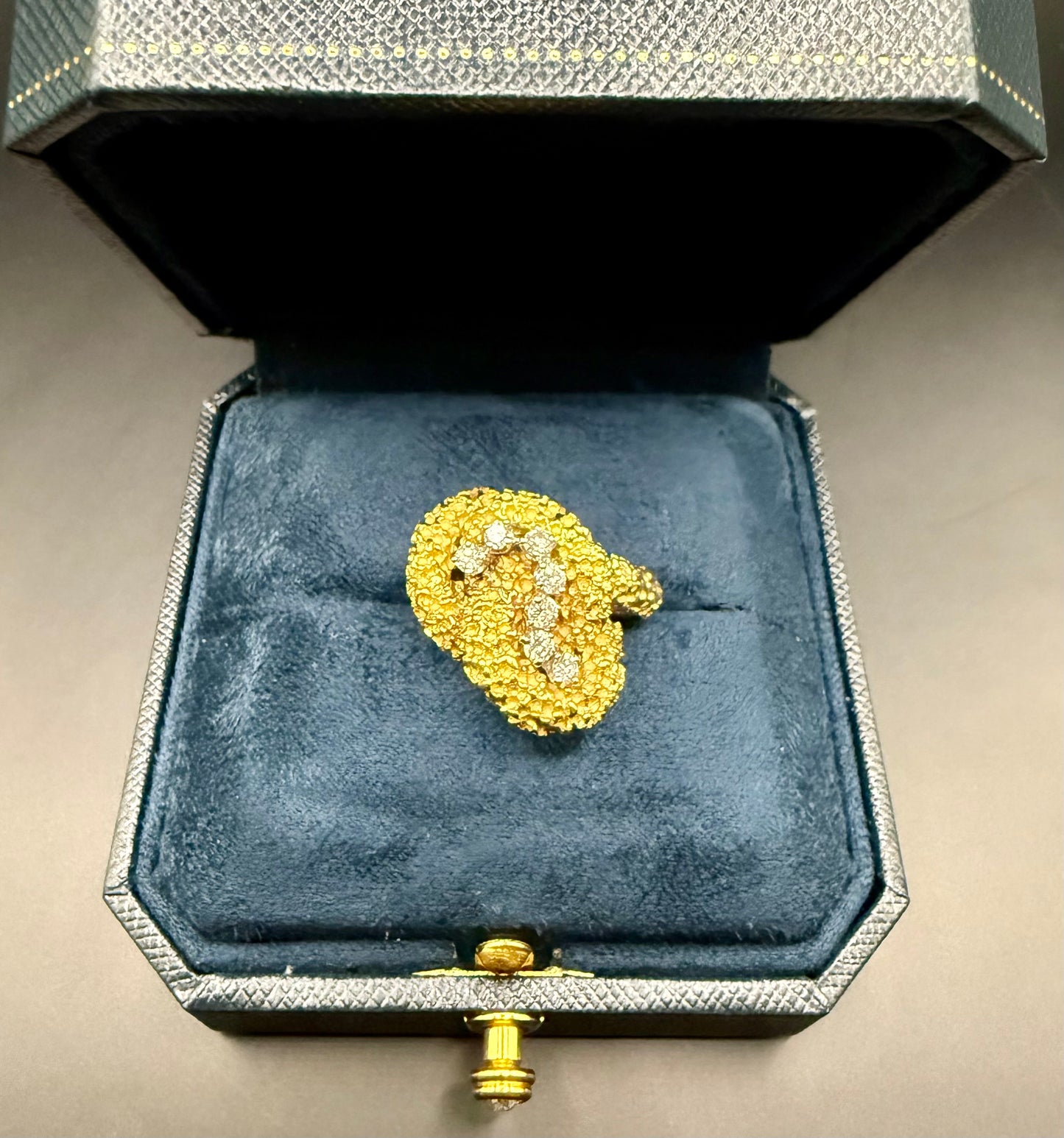 McTeigue 1960s 18K gold and diamond ring catching sunlight, highlighting its sculptural design.