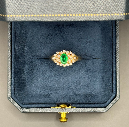 Overhead view of estate 14K yellow gold ring with oval emerald center and diamond halo cluster.