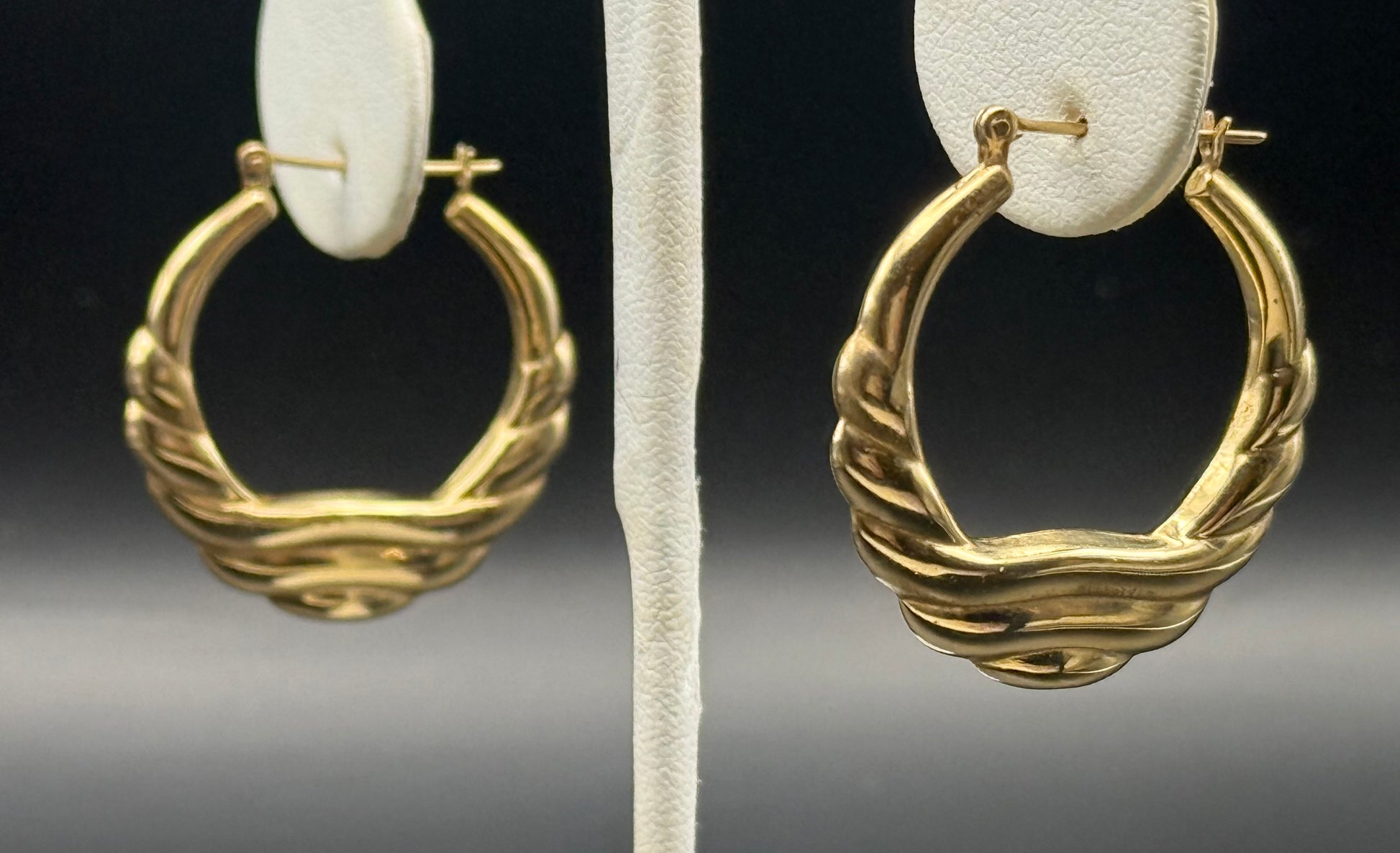 Pair of vintage 14K yellow gold hoop earrings on display stand, statement style