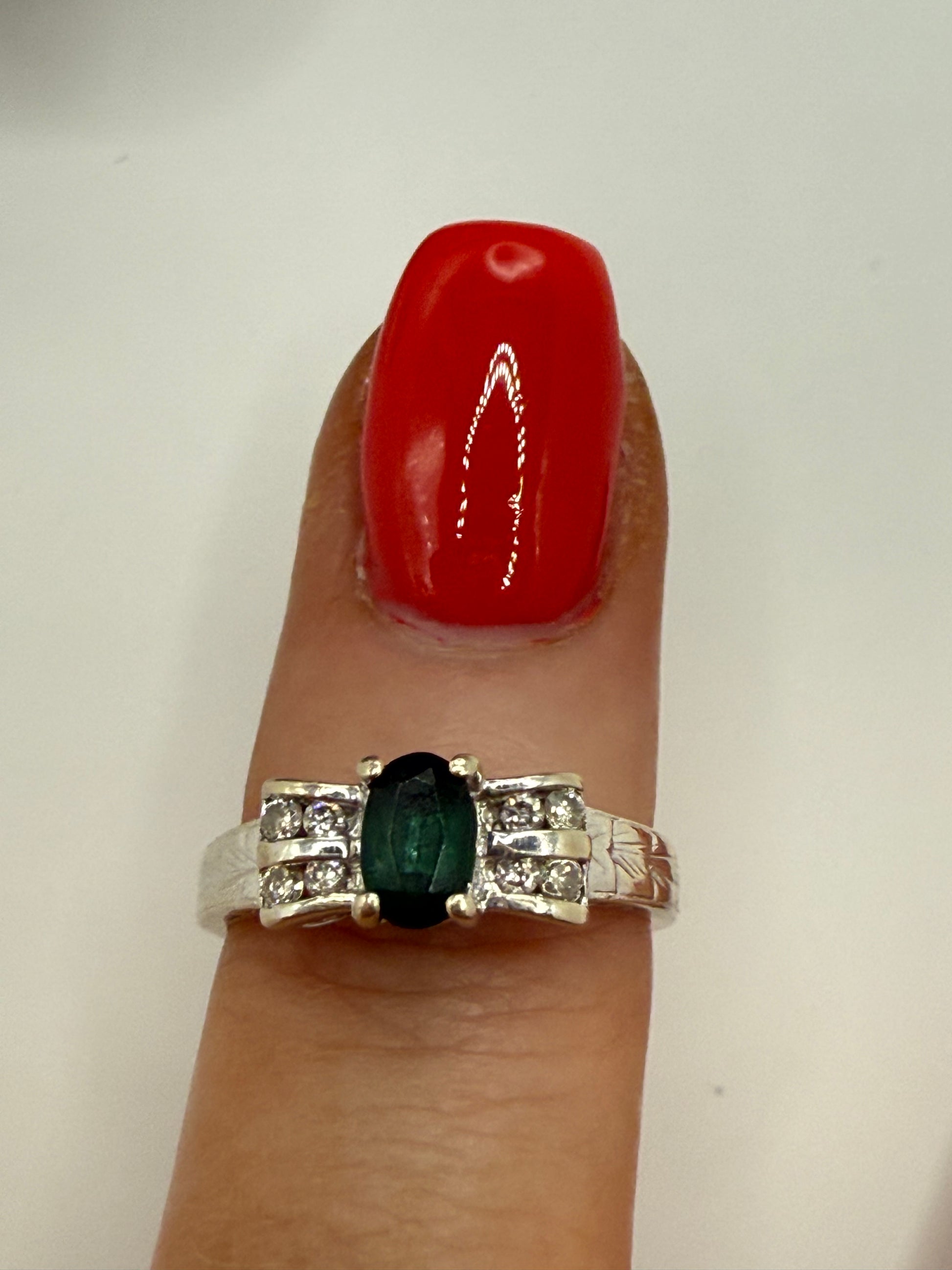 Ring modeled on finger, showing deep blue sapphire and diamond sparkle against engraved white gold band.