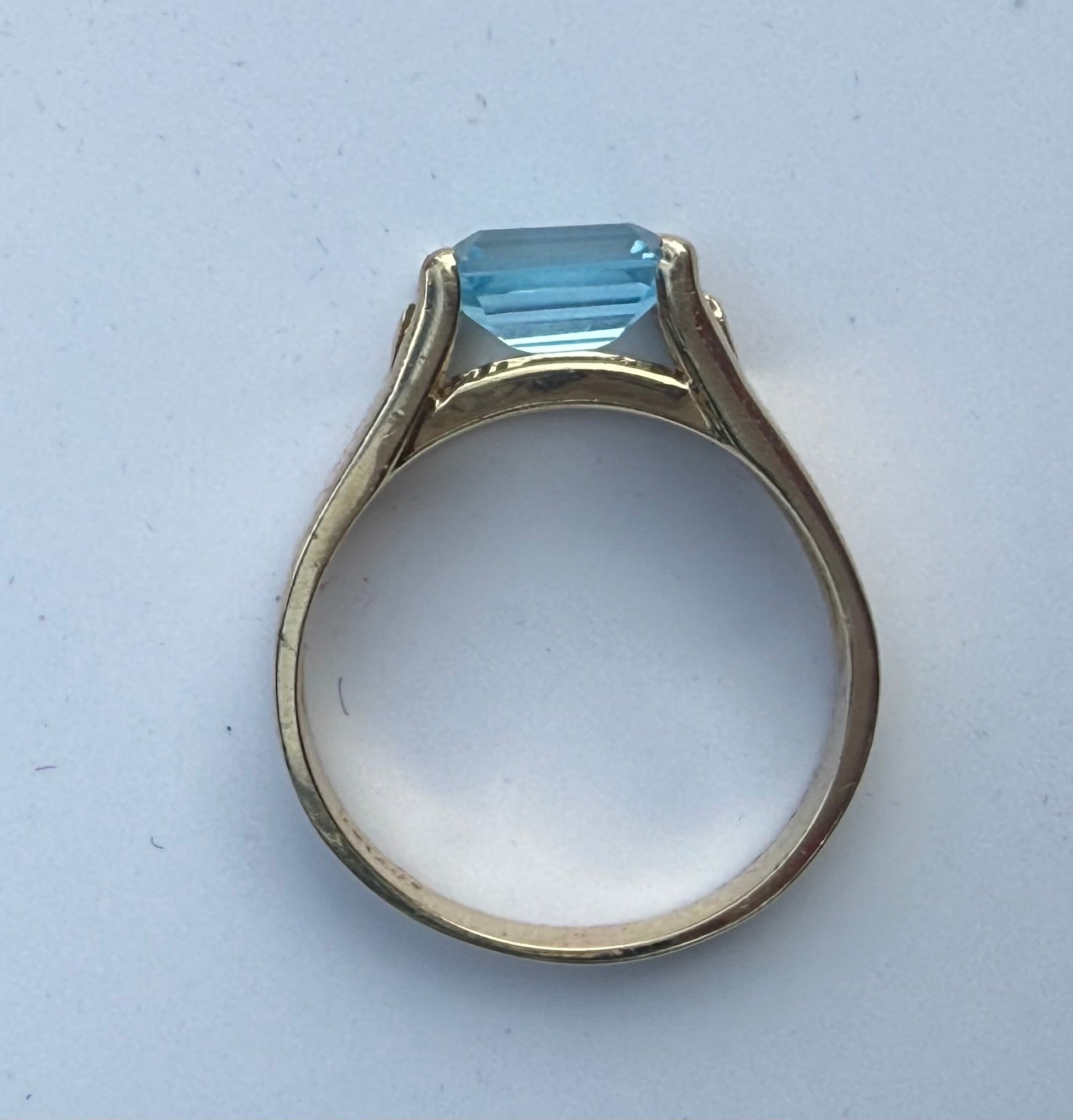Side profile of 14K yellow gold blue topaz and diamond ring showing open under-gallery and high-set stone.