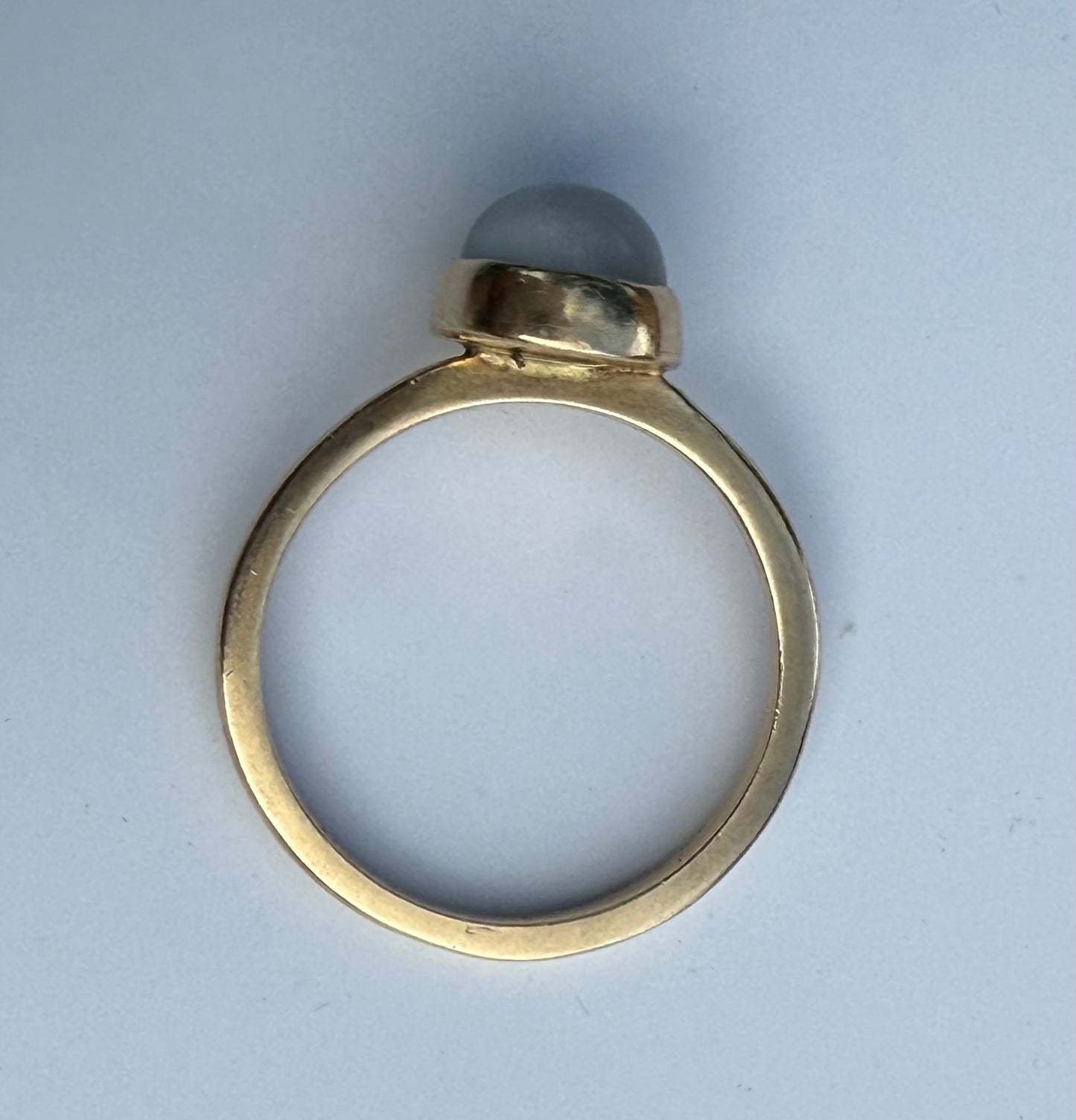 Side profile showing high cabochon moonstone dome set in smooth bezel.