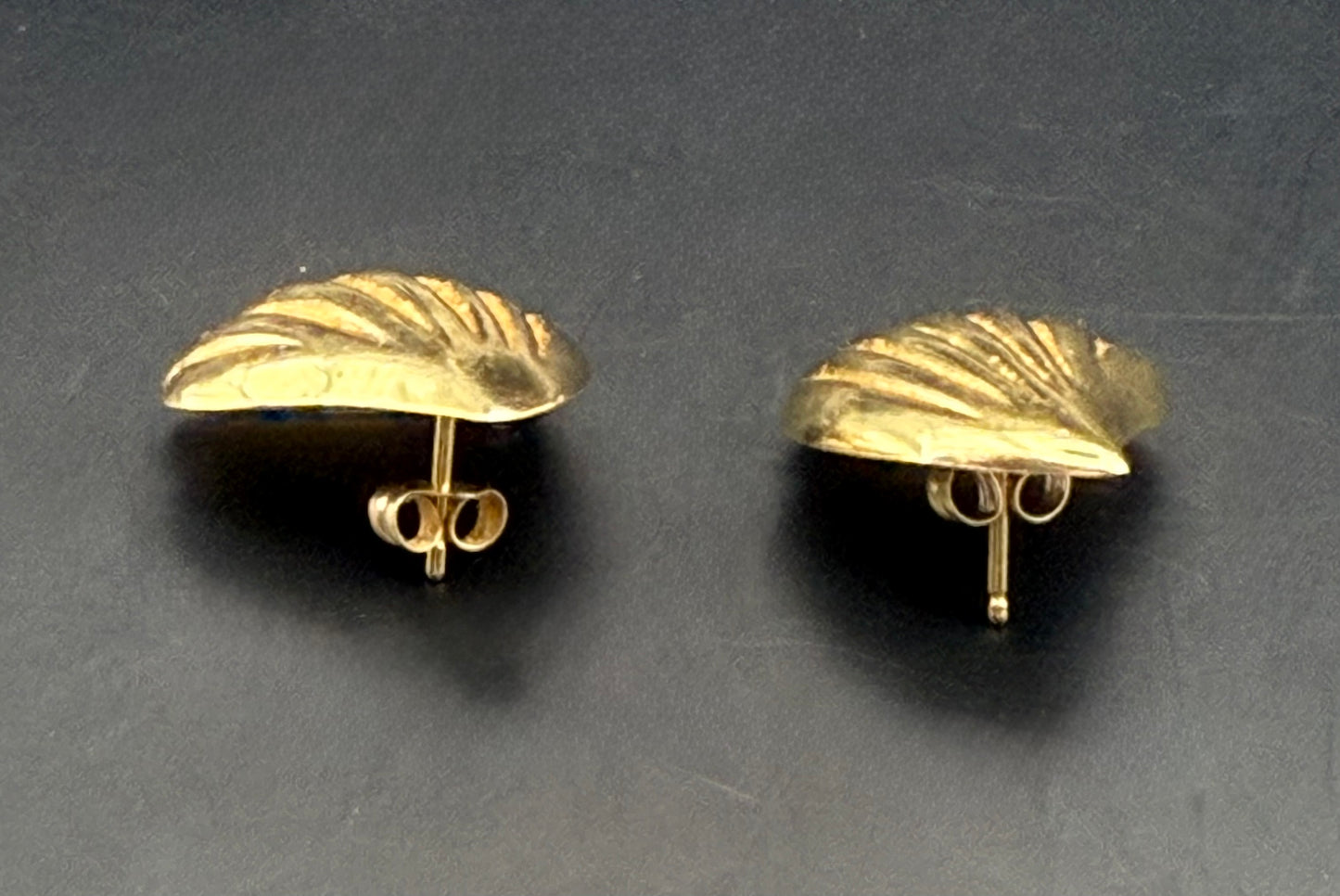Side view of 14K gold shell earrings showing depth and stud backs
