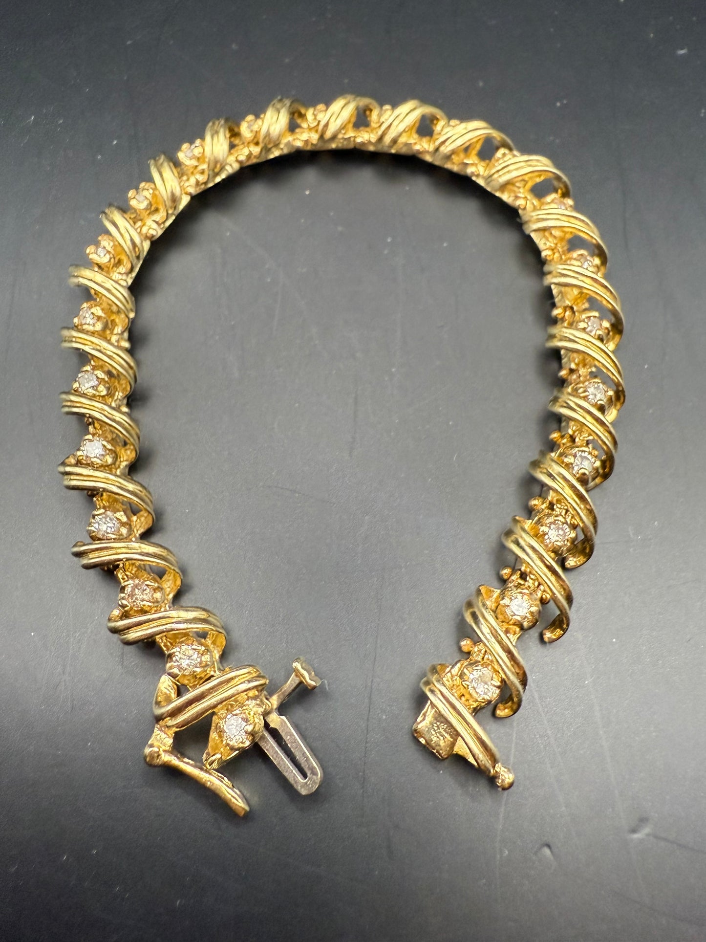 Side view showing diamonds set within curved gold scroll links and box clasp