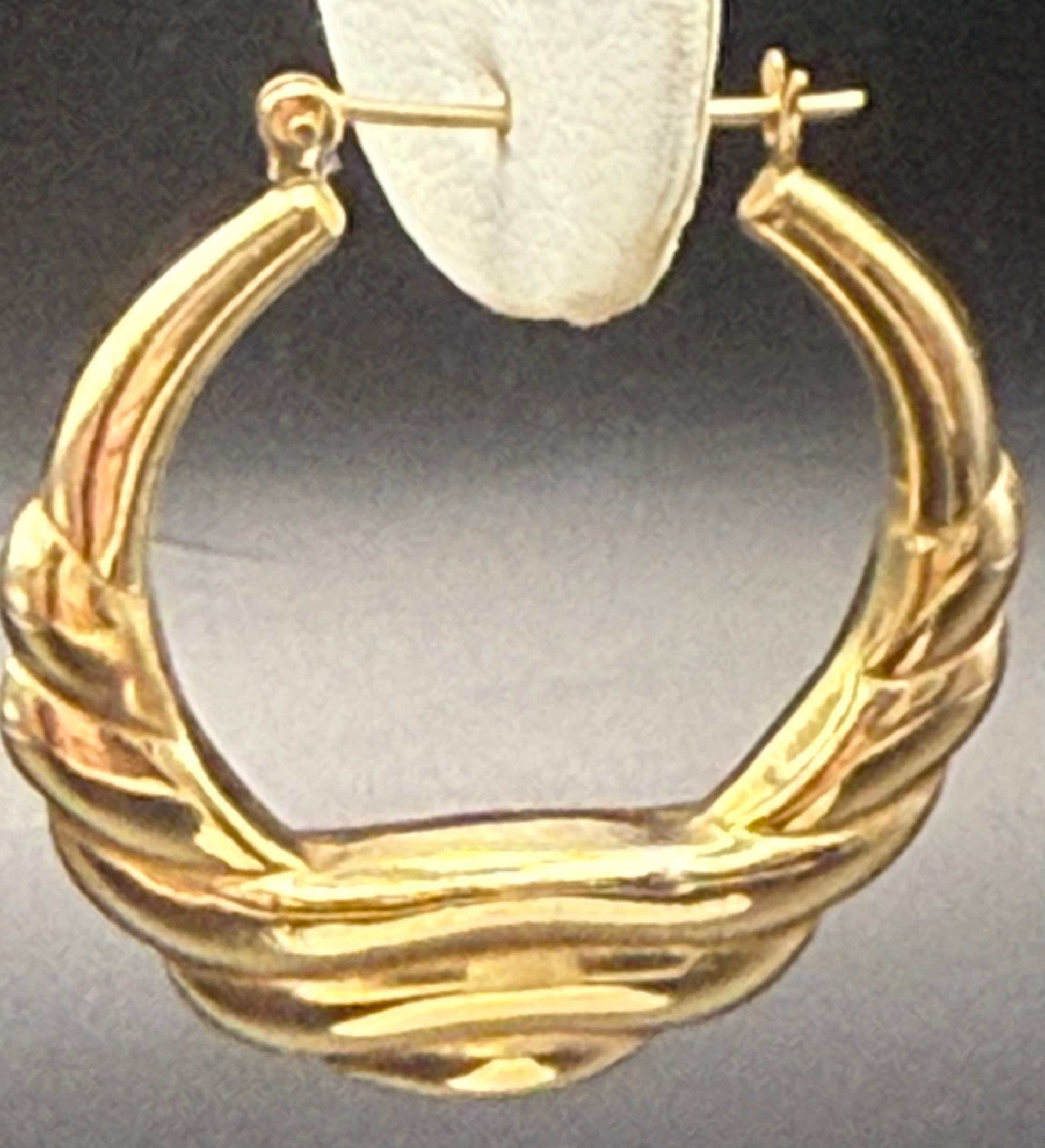 Single 14K yellow gold hoop earring displayed on stand, showing sculptural design