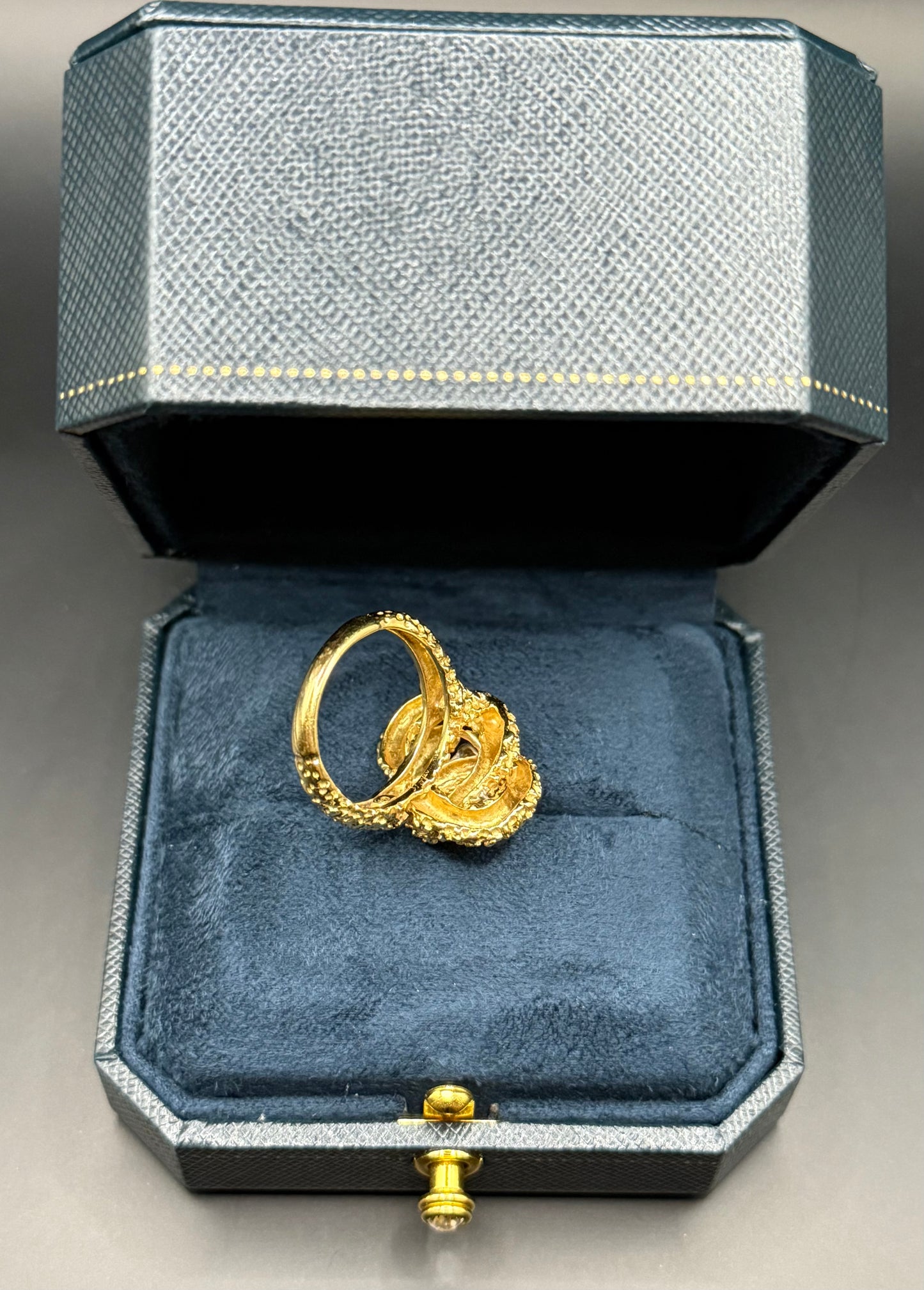 Under view of vintage McTeigue 18K gold and diamond abstract knot ring in navy jewelry box.