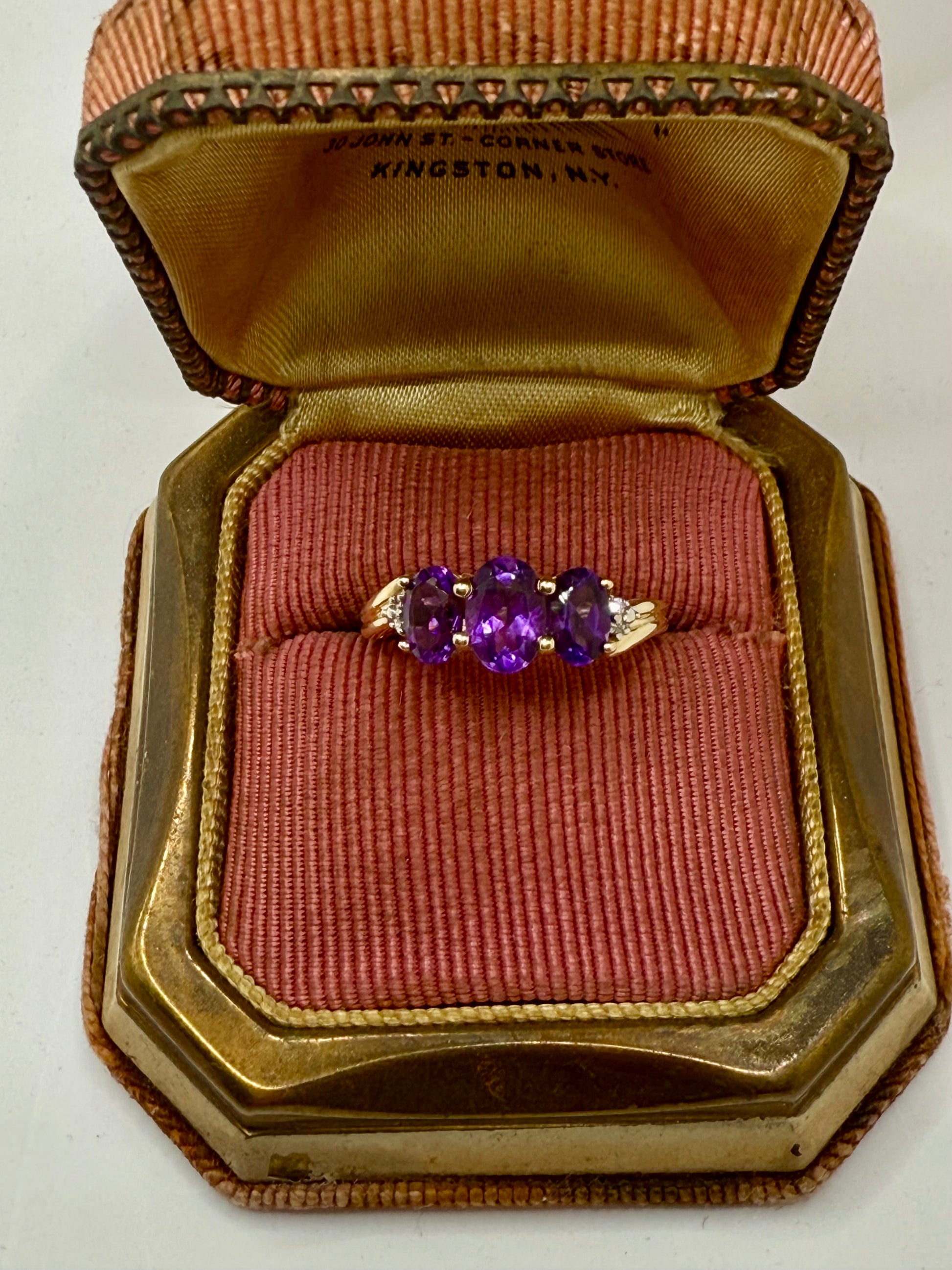 Vintage 3-stone amethyst ring in yellow gold with oval purple gemstones, trilogy design symbolizing past, present, and future.